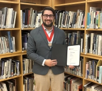 student holding a certificate and medal